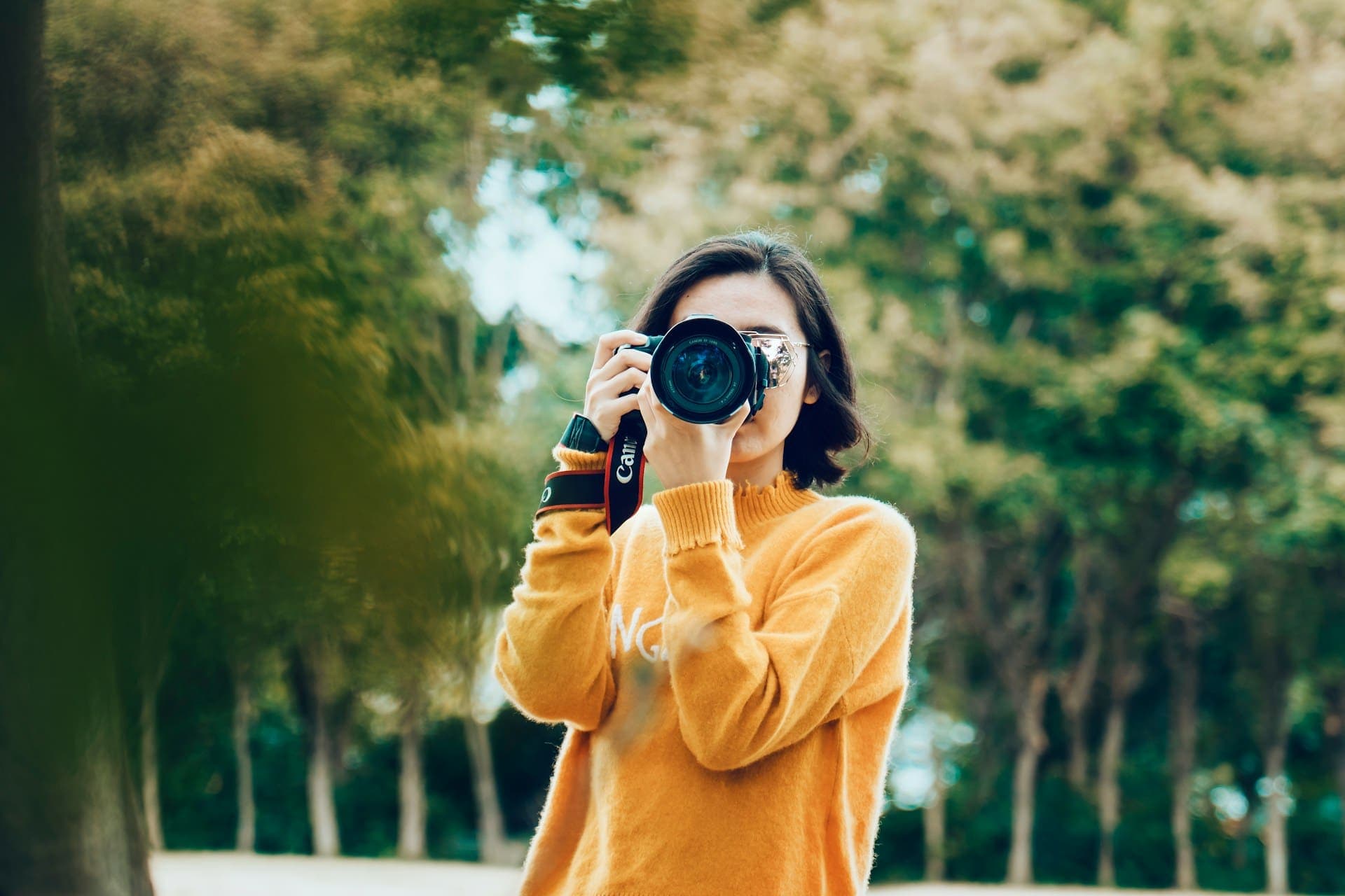 Photography student using a DSLR camera outdoors in a park